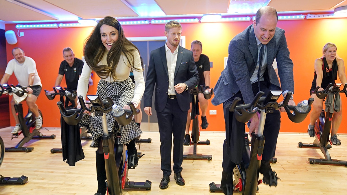 Kate Middleton and Prince William competing in cycling as they smile.