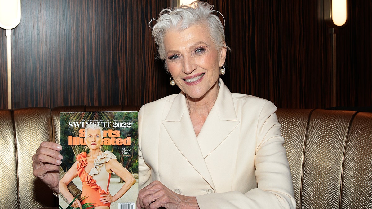 Maye Musk wearing a beige suit and holding her SI Swimsuit cover.