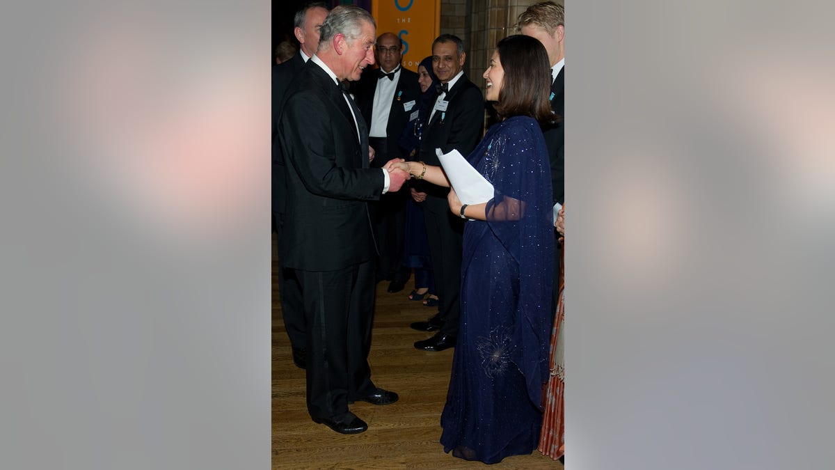 Mishal Husain wearing a blue gown being greeted by King Charles.