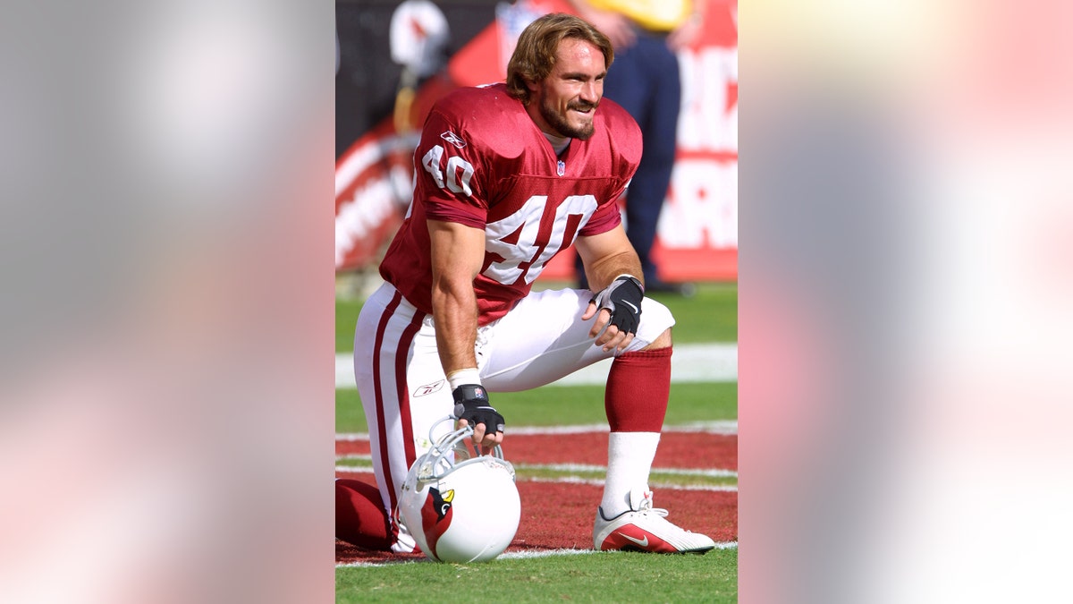 Pat Tillman in NFL gear kneeling on the field.