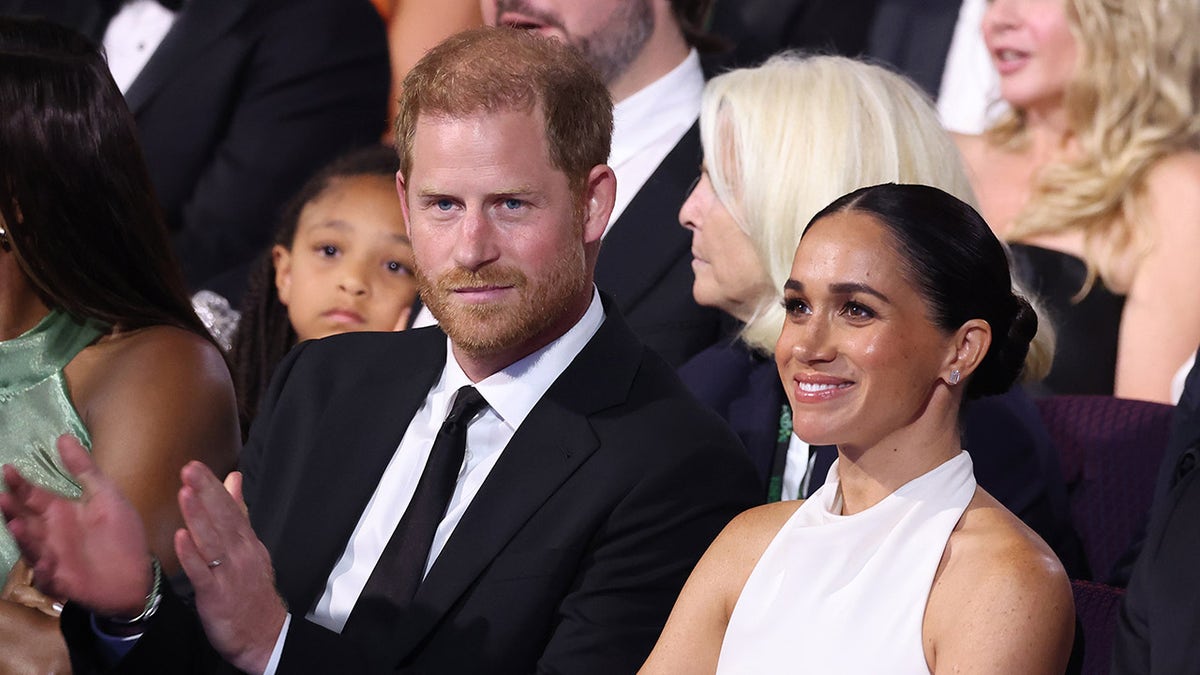Prince Harry and Meghan Markle sitting together in an audience at an event.