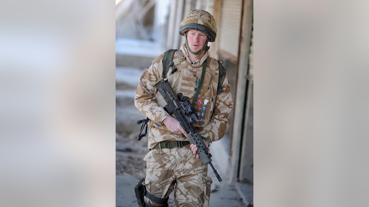Prince Harry in military gear holding a gun.
