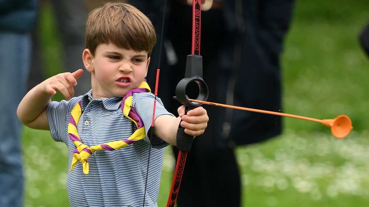 Prince Louis trying archery with a serious face and a striped shirt.