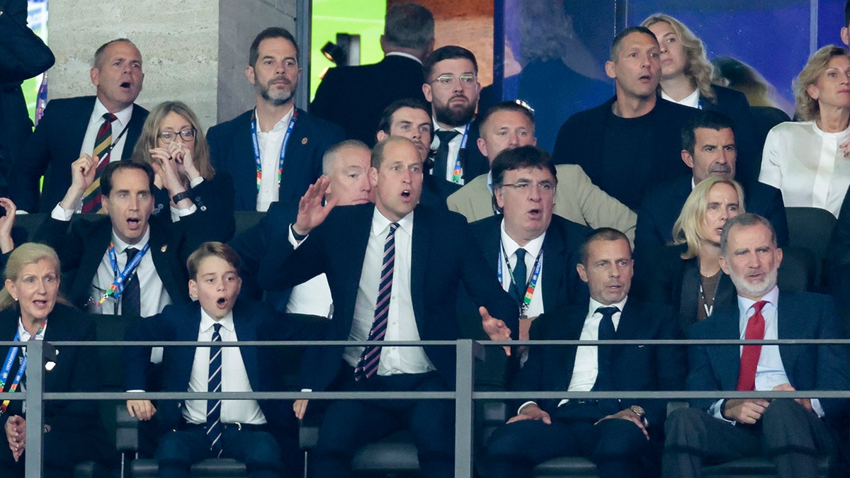 Prince George and Prince William appear stunned in suits as they cheer on from the stadium
