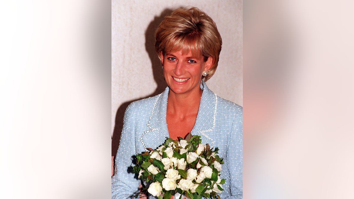 A close-up of Diana wearing a powder blue dress holding a bouquet of white flowers.