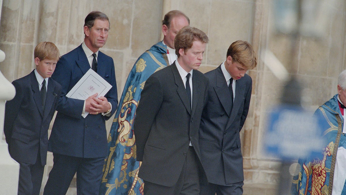Prince Charles walking with Prince Harry, Prince William and Charles Spencer with their heads down during Princess Dianas funeral.