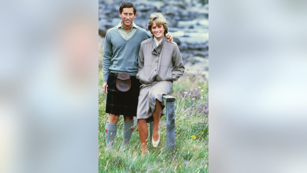 Princess Diana in a khaki jacket and matching skirt smiling next to Prince Charles in traditional Scottish wear.