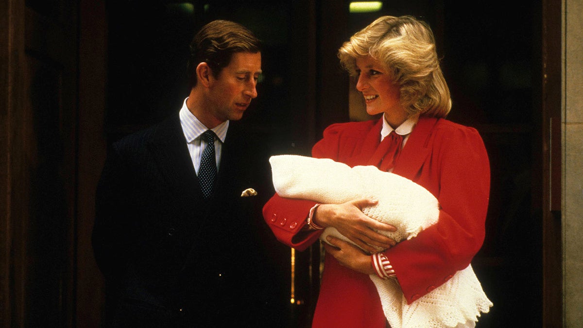 Princess Diana holding baby Prince Harry as Prince Charles looks at his son.