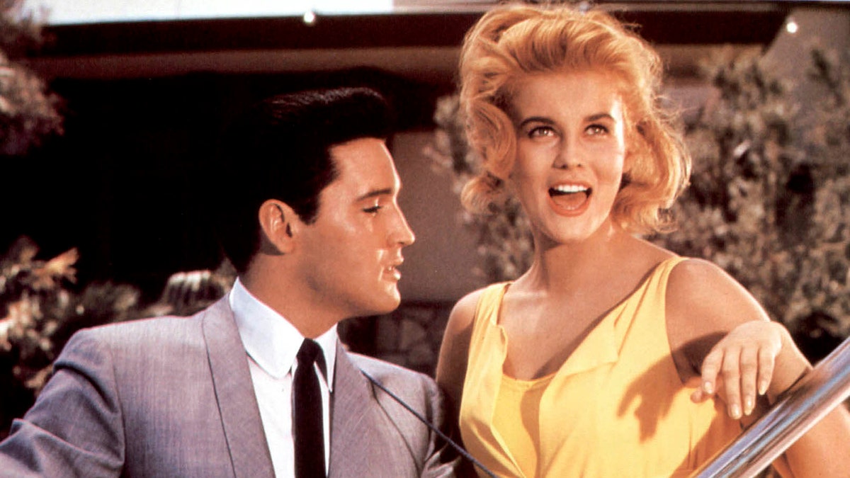 Ann-Margret singing as Elvis Presley looks at her in a grey suit.