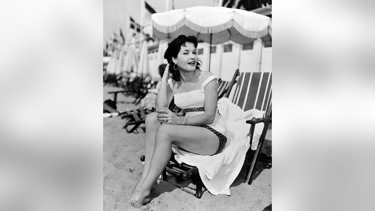 Yvonne Furneaux posing as a pinup on the beach.