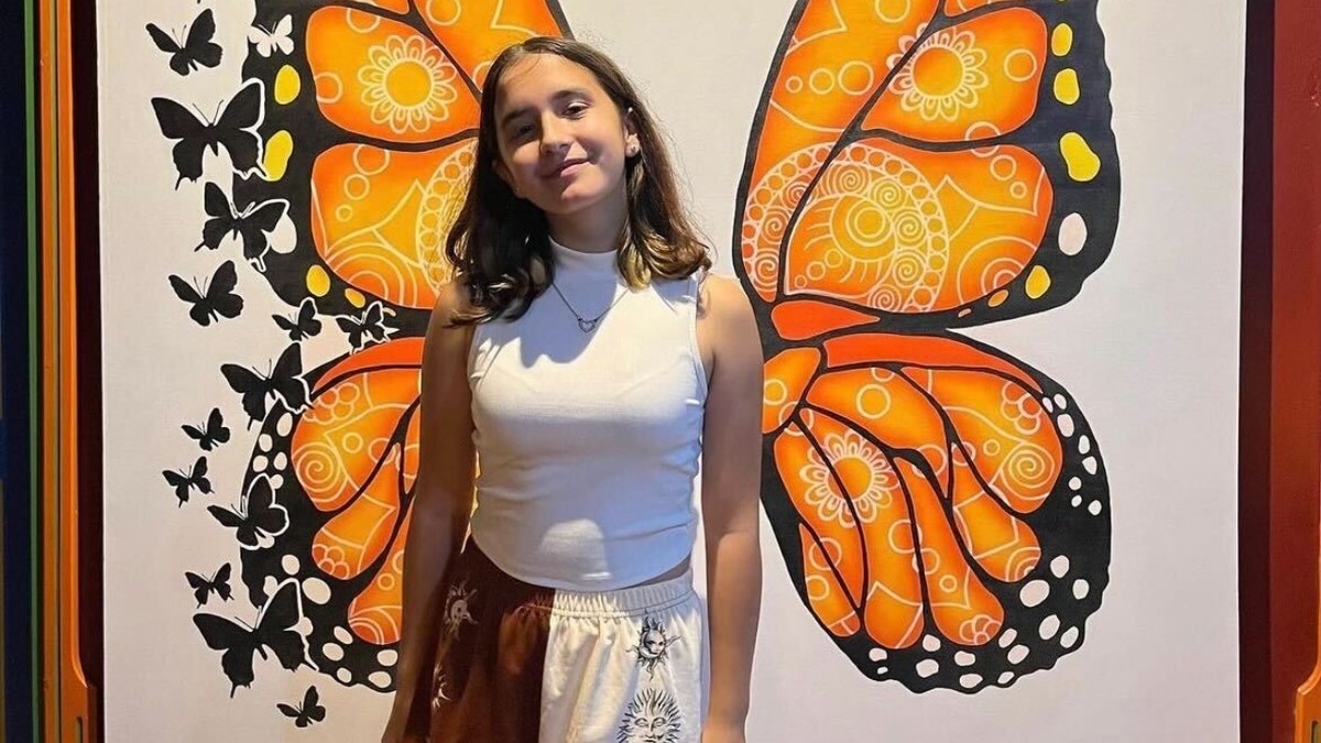 Jocelyn Walters poses in front of a butterfly mural