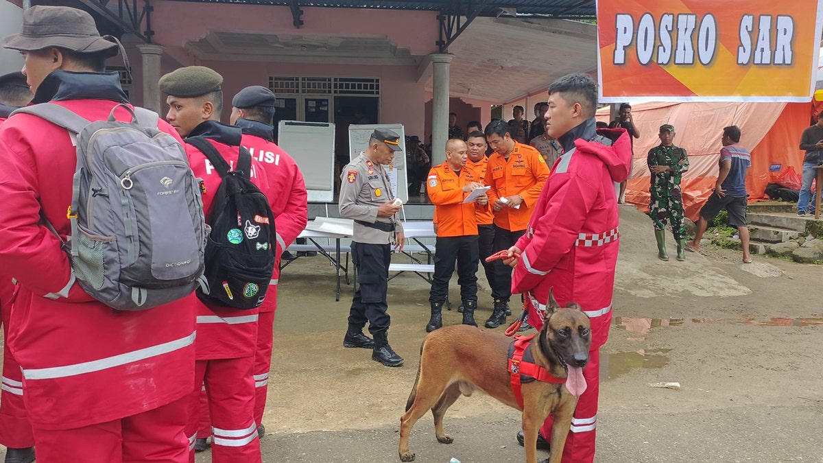 Trabajadores vestidos con uniformes rojos de la Agencia Nacional de Búsqueda y Rescate de Indonesia se preparan para dirigirse al lugar de un deslizamiento de tierra mortal.