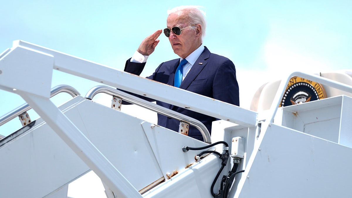 President Joe Biden saluting from steps to Air Force One