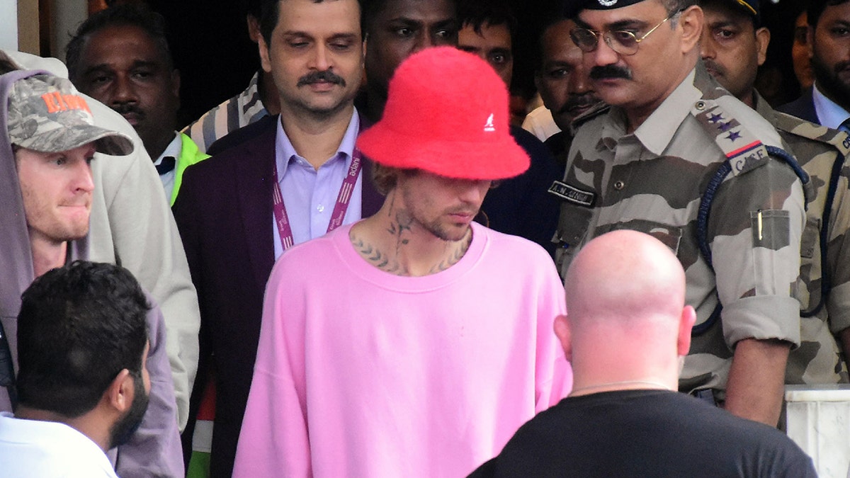 Justin Bieber con un gorro de cubo rojo y un jersey rosa entre la multitud