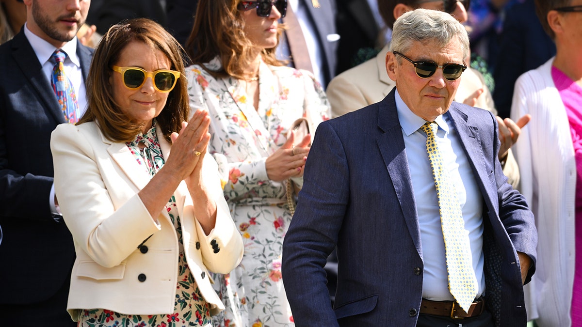 Carole Middleton klaszcze i nosi żółte okulary przeciwsłoneczne obok męża Michaela Middletona w niebieskim garniturze i żółtym krawacie na Wimbledonie