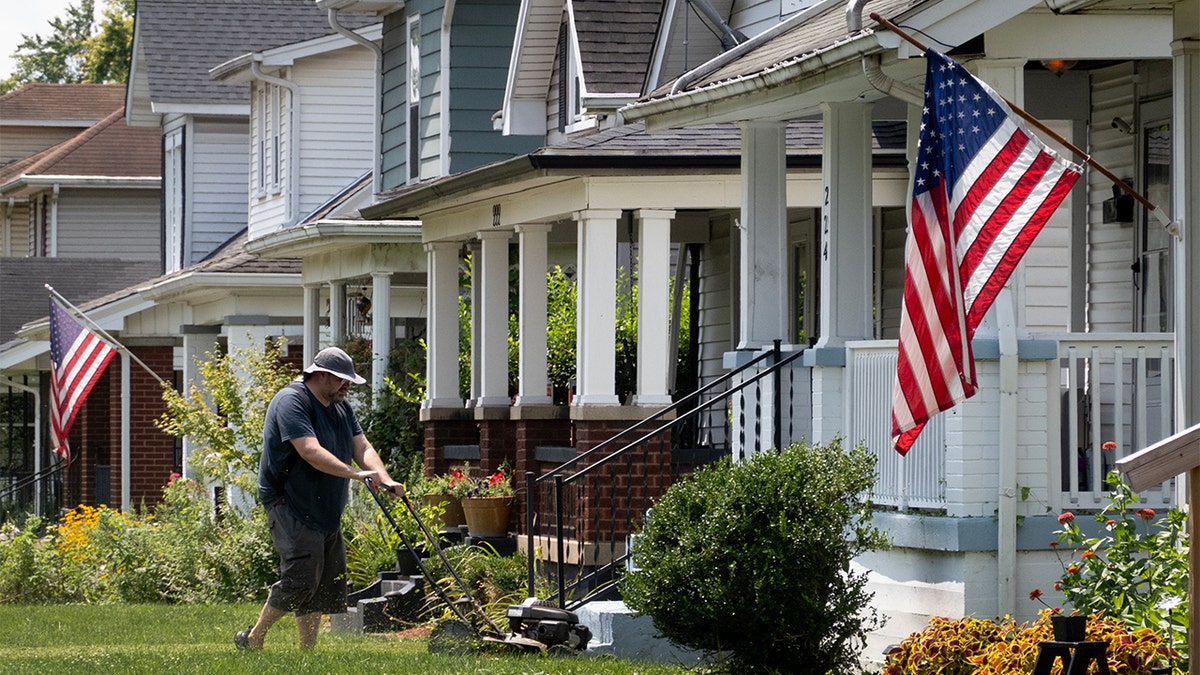 A man mowing his lawn in front of his home.