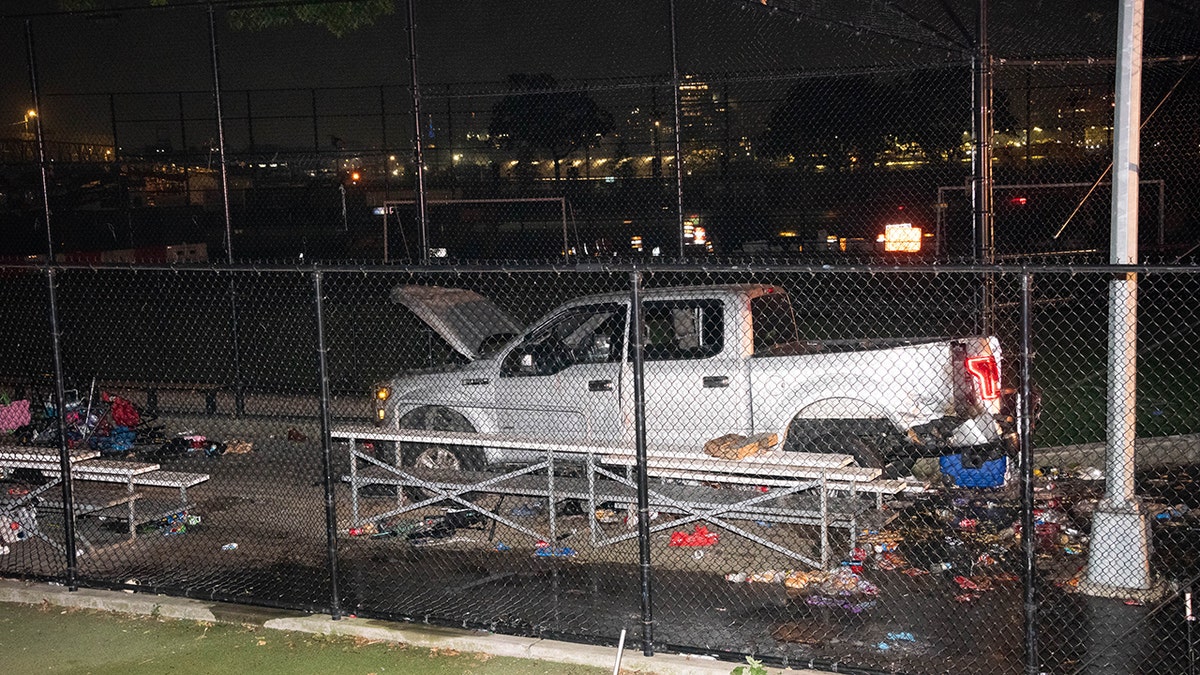 Police investigate a crash scene with a white truck in a park