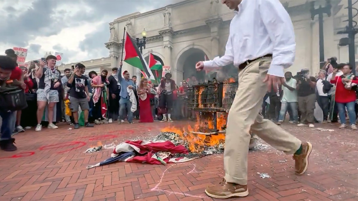 An unnamed patriot reaches down to rescue the American flag from being burned