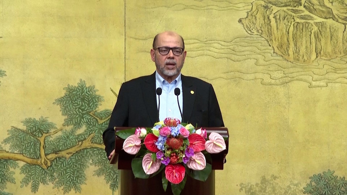 Senior Hamas Official Mousa Abu Marzouk stands at a podium adorned with flowers.