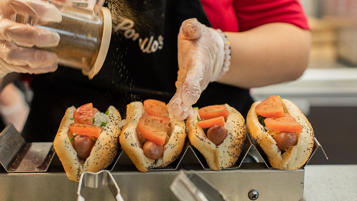 Person making Chicago-style hot dogs.