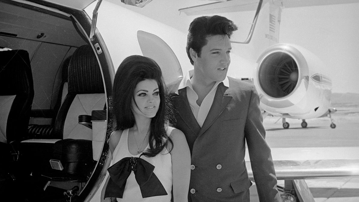 Priscilla Presley and Elvis stand in front of a plane