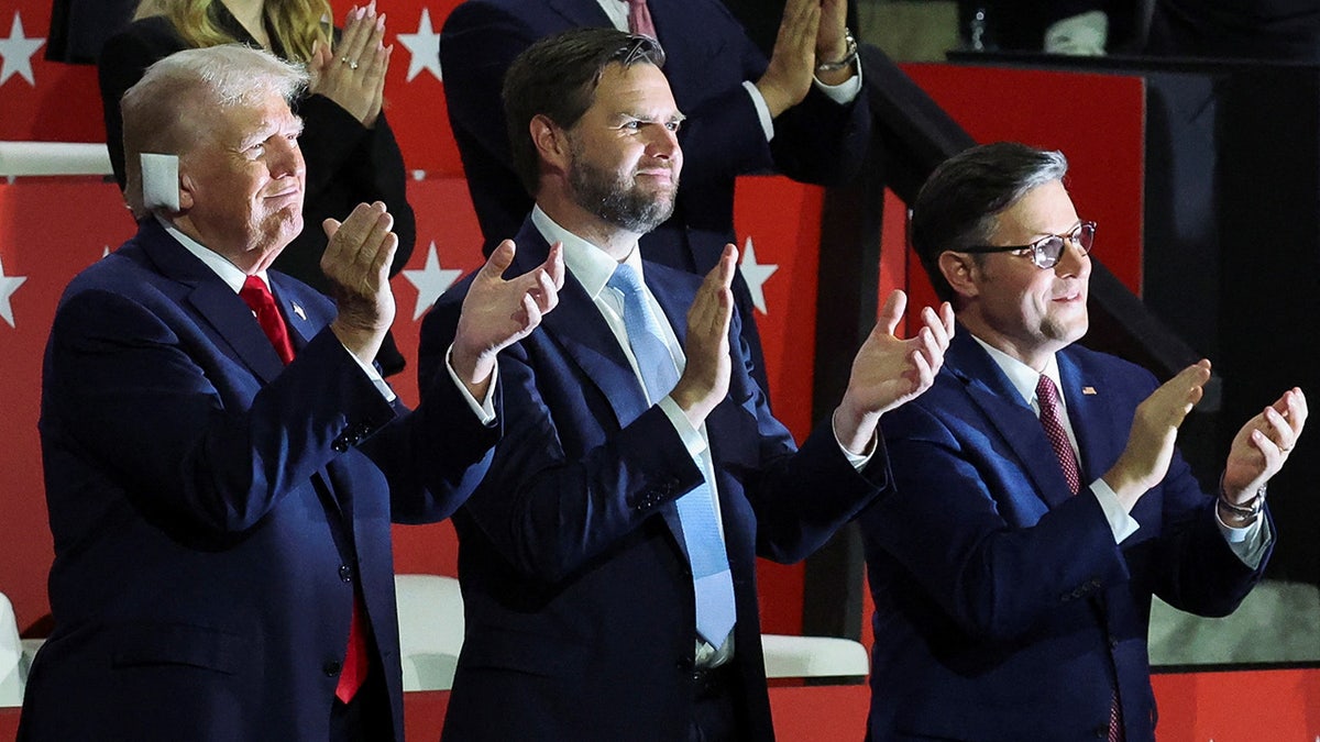 Republican presidential nominee and former U.S. President Donald Trump applauds with Republican vice presidential nominee J.D. Vance and House Speaker Mike Johnson during Day 1 of the Republican National Convention
