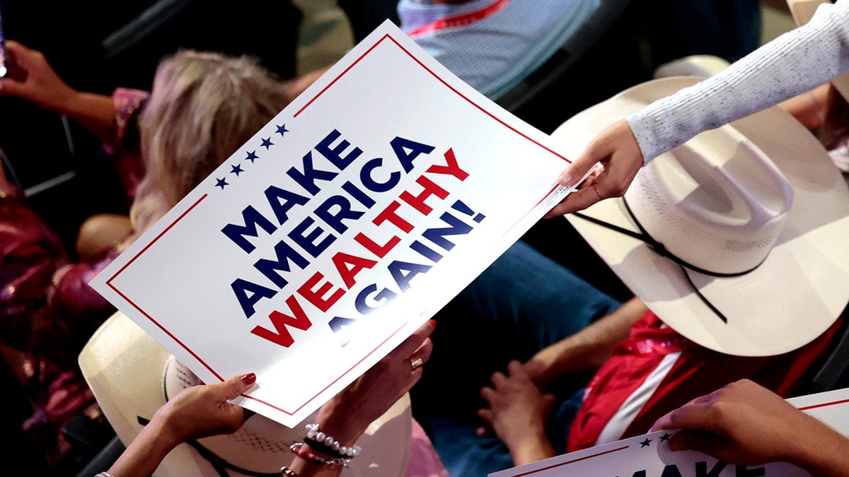 A "Make America Wealthy Again" sign is distributed to a delegate during the Republican National Convention