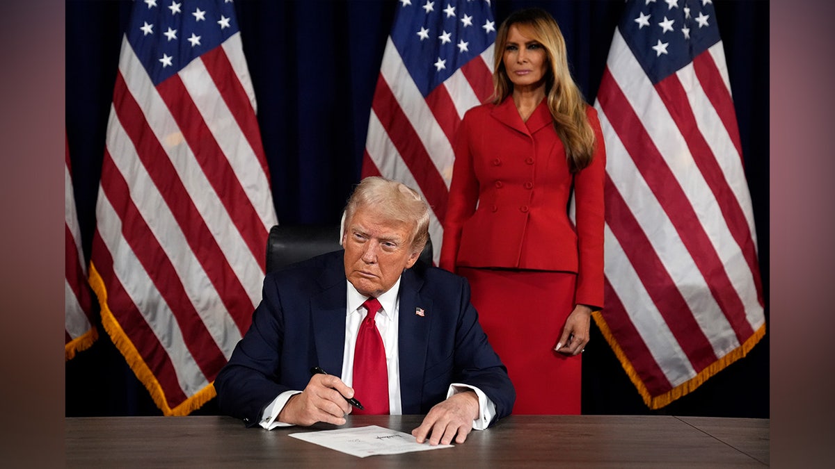 As Melania Trump watches, Republican presidential candidate former President Donald Trump signs paperwork to officially accept the nomination during the final day of the Republican National Convention