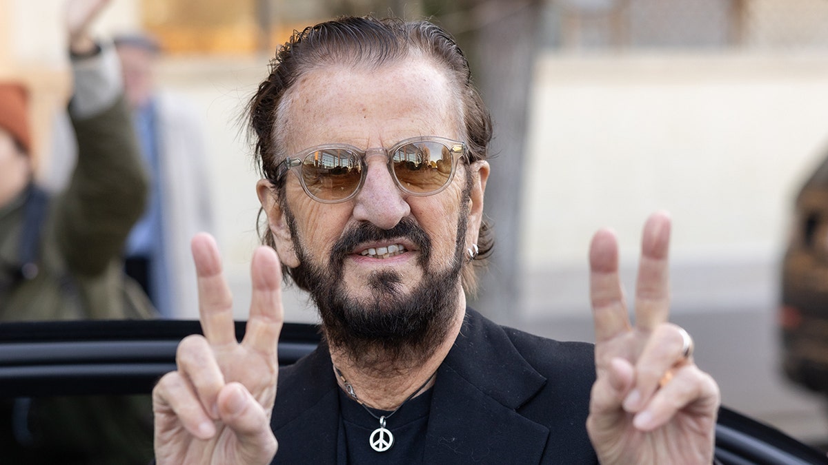 Primer plano de Ringo Starr haciendo señales de paz