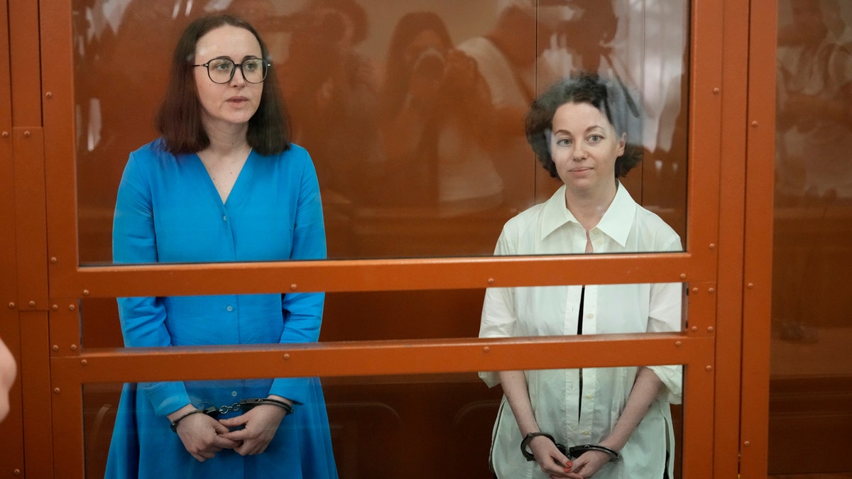 Theater director Zhenya Berkovich, right, and playwright Svetlana Petriychuk are seen in a glass cage prior to a hearing in a court in Moscow.