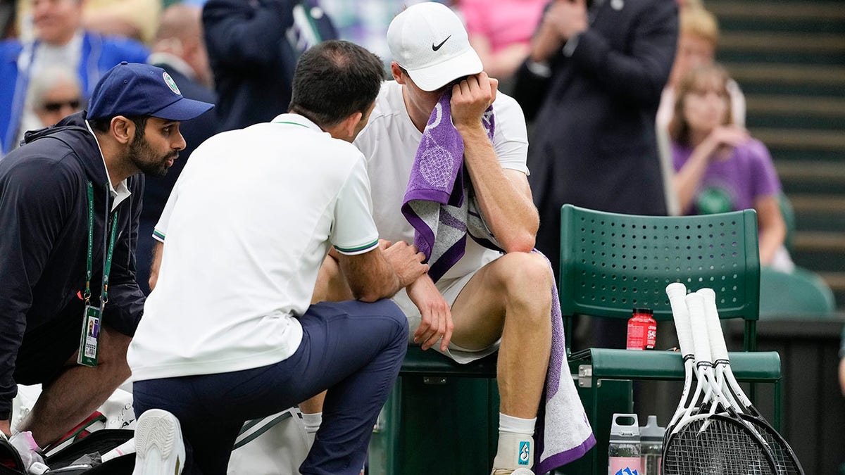 Jannik Sinner receives treatment from trainer