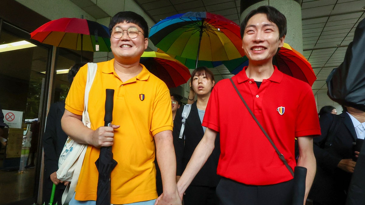A same-sex couple holds hands as they leave the Supreme Court Building in Seoul.