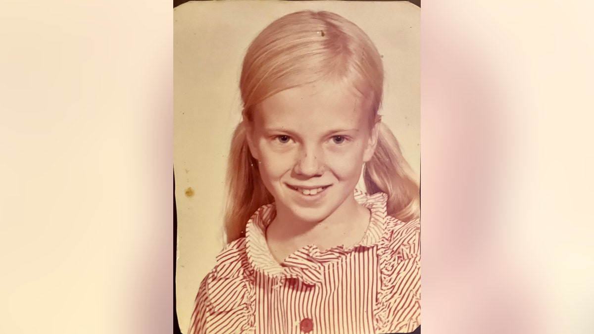 A vintage portrait of a little girl wearing a red and white striped blouse.