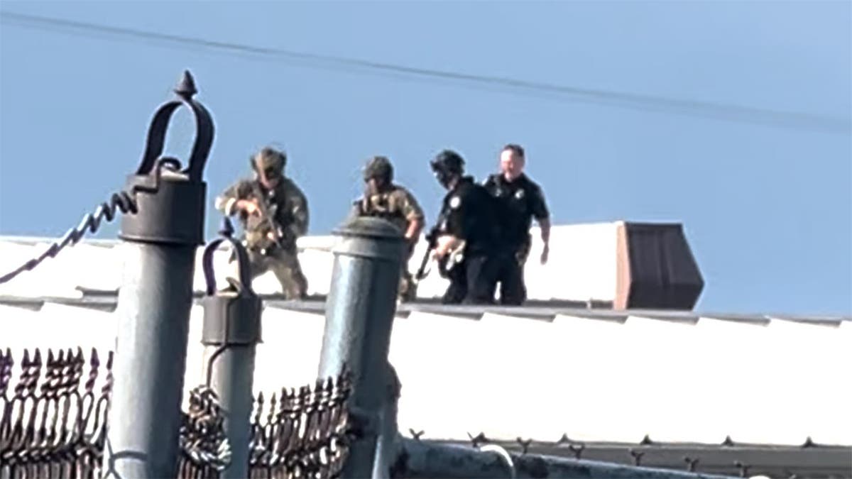 Law enforcement officers stand over the body of would-be Trump assassin, Thomas Crooks on the roof of a building