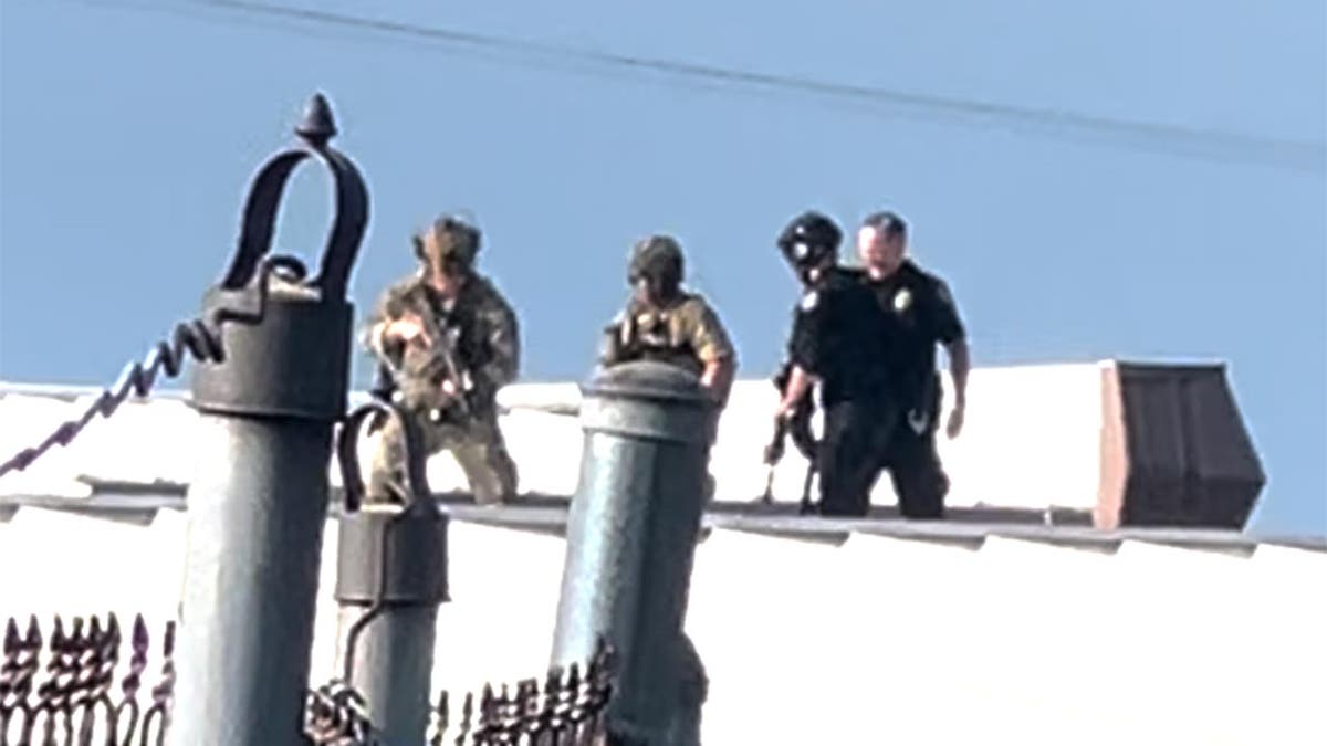 Law enforcement officers stand over the body of would-be Trump assassin, Thomas Crooks on the roof of a building