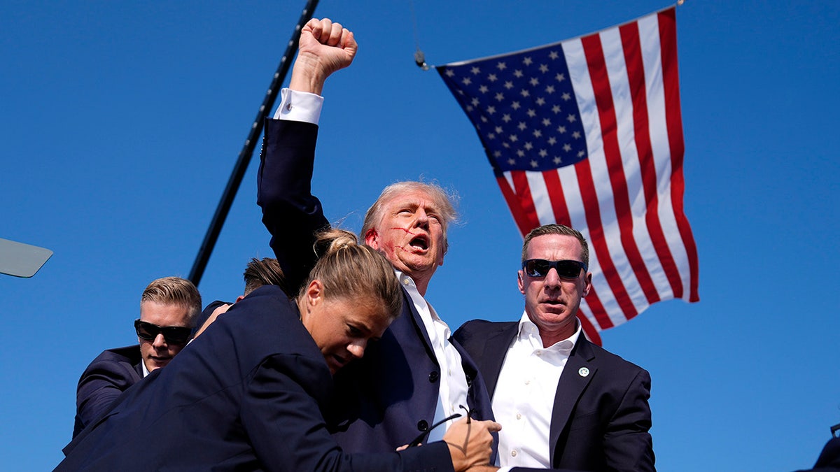 Former President Donald Trump is surrounded by U.S. Secret Service agents at a campaign rally on Saturday, July 13, 2024, in Butler, Pennsylvania, moments after Trump's ear was grazed by a gunman's bullet. 