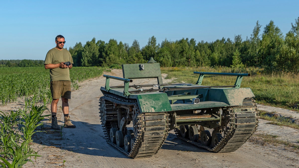 Andrii Denysenko, director general de la oficina de diseño y producción "UkrPrototyp", junto a Odyssey, un prototipo de dron terrestre de 1.750 libras que parece un tanque en miniatura, en un campo de maíz del norte de Ucrania.