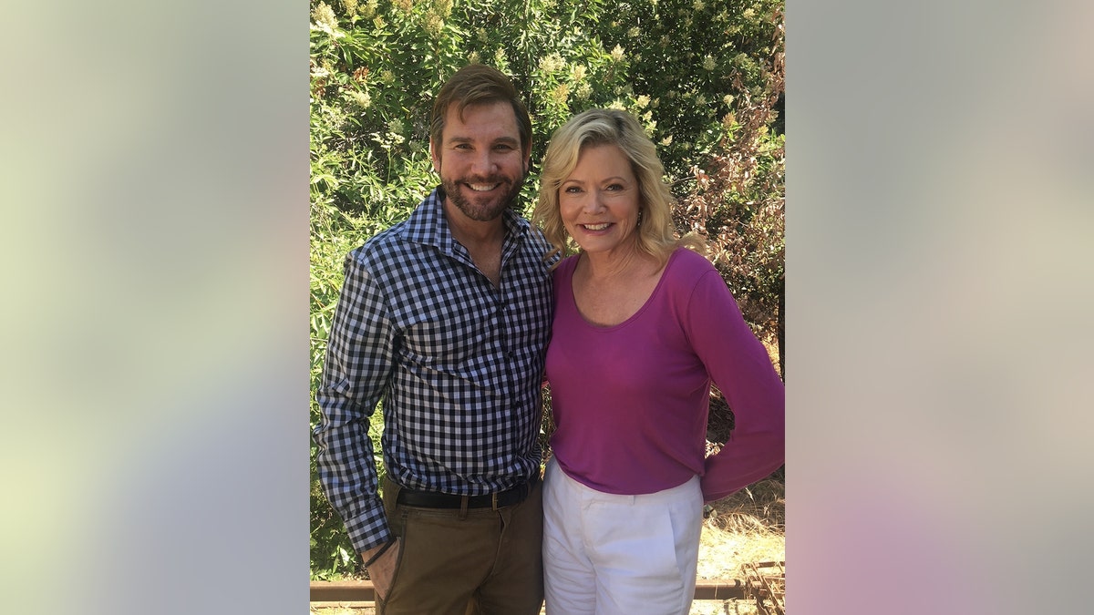 Sheree J. Wilson in a purple blouse and white pants posing next to William Keck in a plaid blue and white shirt and khacki pants.