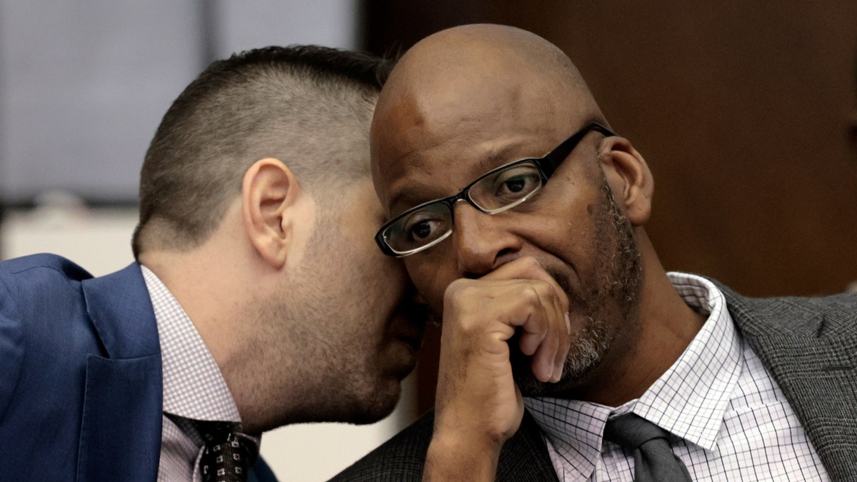 Justin Bonus, left, attorney for Christopher Dunn, right, whispers to his client during the first day of his hearing to decide whether to vacate his murder conviction.