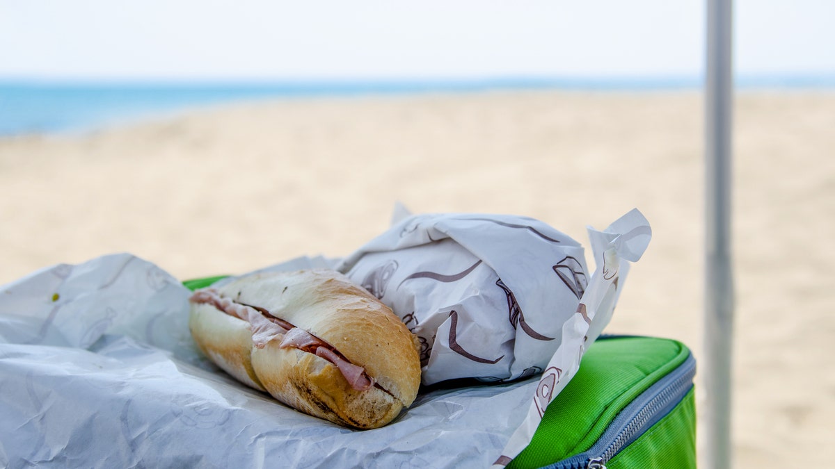 A sandwich on top of a cooler at the beach