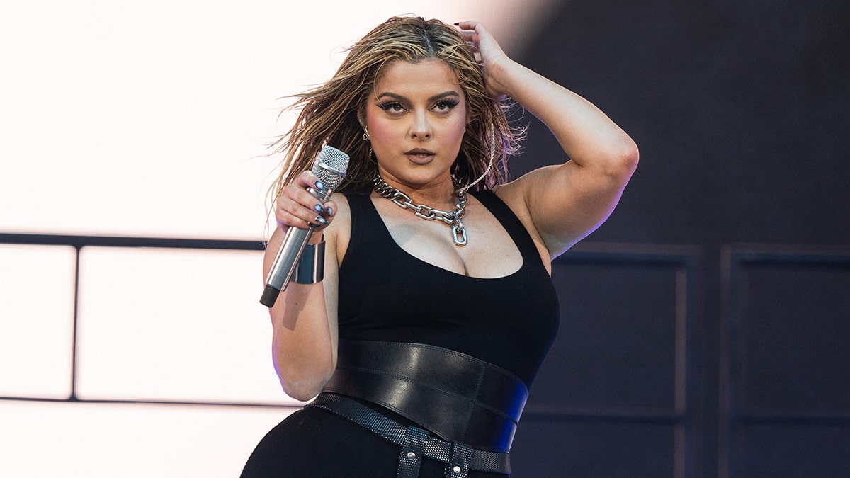 Bebe Rexha sujeta su micrófono en el escenario mientras actúa sobre el escenario vestida de negro en Coachella