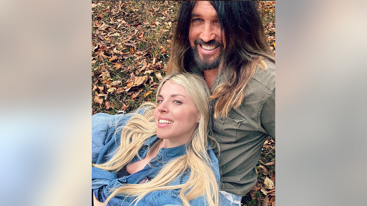 Firerose in a denim shirt leans against husband Billy Ray in the leaves