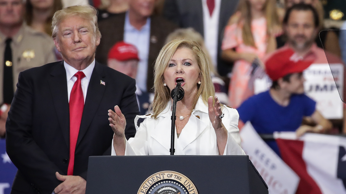 Marsha Blackburn speaking at podium as President Trump looks on from behind left in 2018 photo