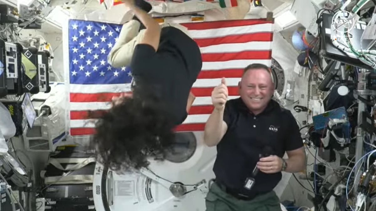 Astronaut Suni Williams does backflips while Astronaut Butch Wilmore laughs and gives a thumbs up. 