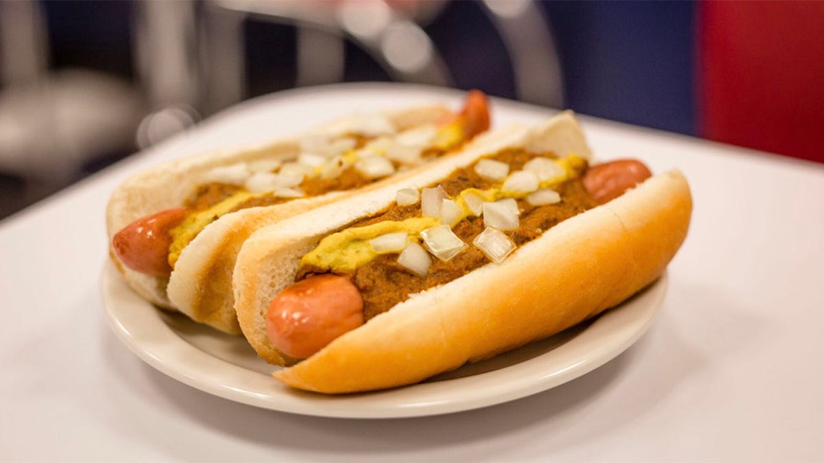 Two Coney Island dogs topped with chili, mustard, and onion.