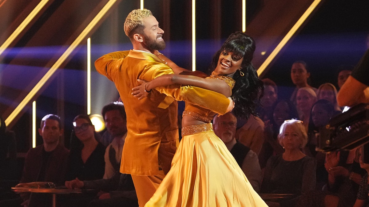 Artem Chigvintsev in a gold/yellow suit dances with Charity Lawson in a gold/yellow dress during 'Dancing with the Stars'
