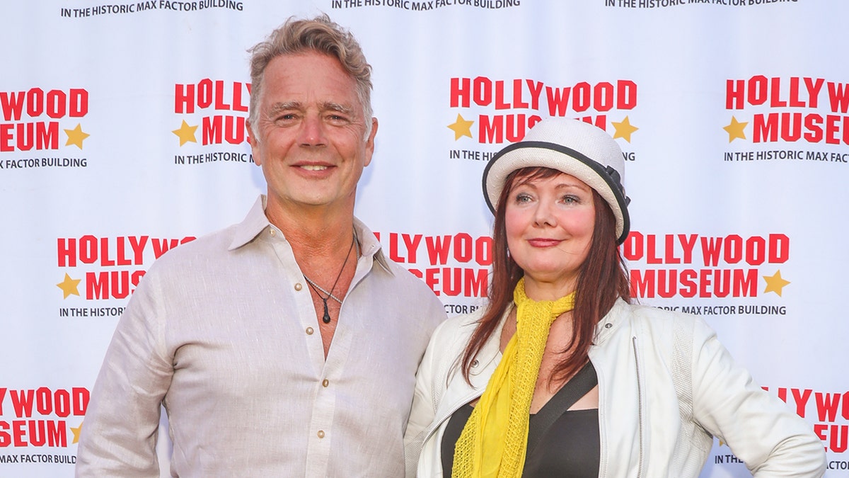 Aktor John Schneider mengenakan kemeja linen dengan Dee Dee Sorvino di sisinya.