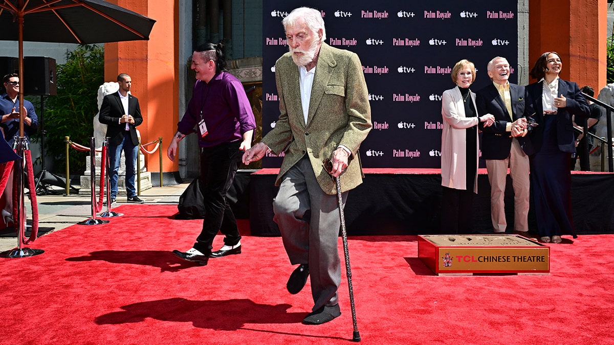 Dick Van Dyke in a green jacket on the red carpet walking with some pizazz and a cane