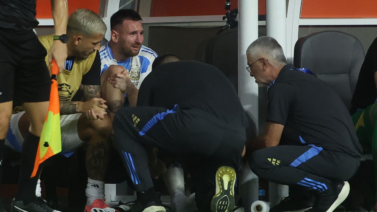 Lionel Messi cries while being tended to by trainers