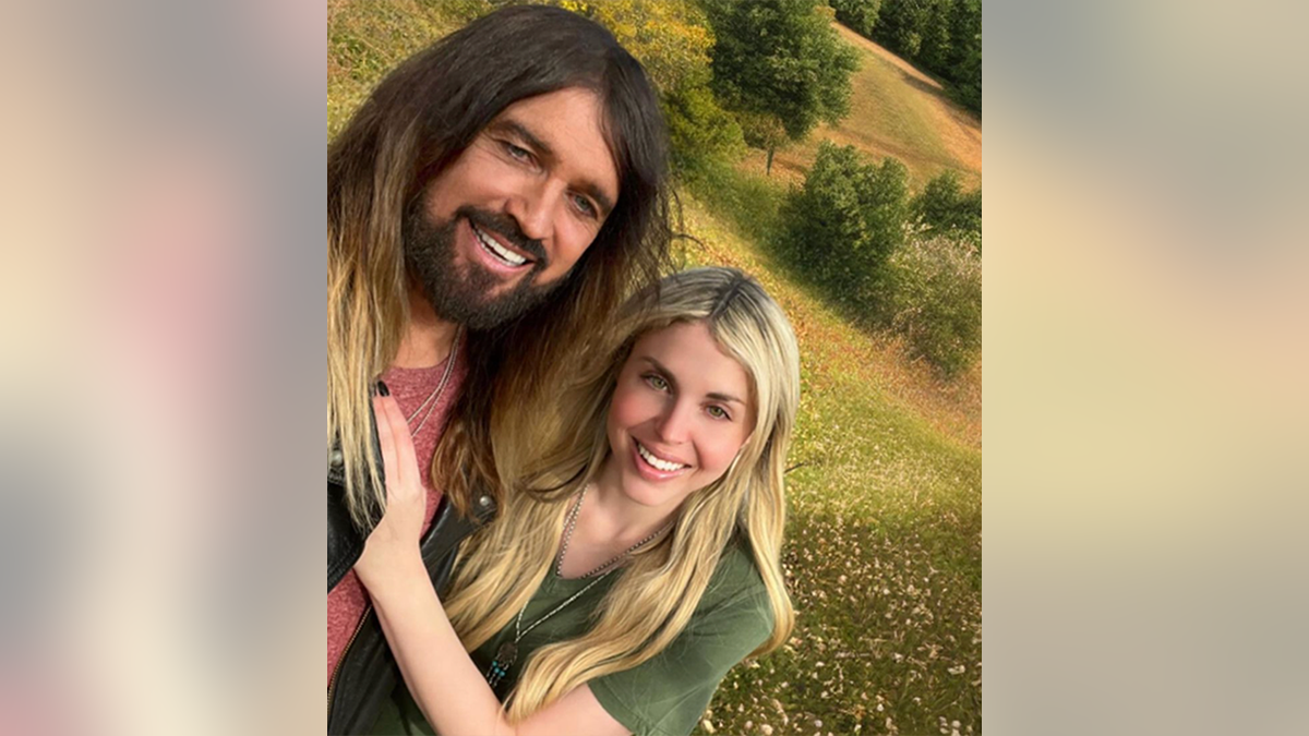 Firerose in a green t-shirt puts her hands on Billy Ray's chest